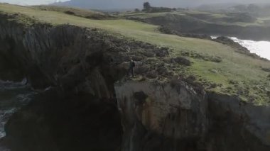 Asturias 'ın engin ve sakin okyanusuna bakan engebeli kayalık bir kıyı şeridinde yalnız bir figür duruyor. Sahne yalnızlığı, keşfi ve doğanın güzelliğini yakalar..