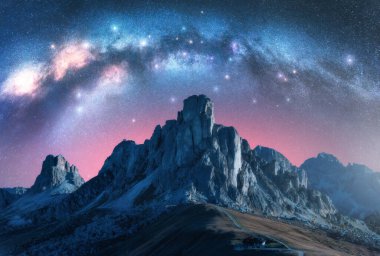 Samanyolu Galaksisi yaz gecelerinde görkemli dağların üzerinde parlıyor. Paso Giau, Dolomitler, İtalya. Parlayan samanyolu dönümlü gece manzarası, parlak yıldızlar, pembe ışık, yüksek kayalıklı vadi