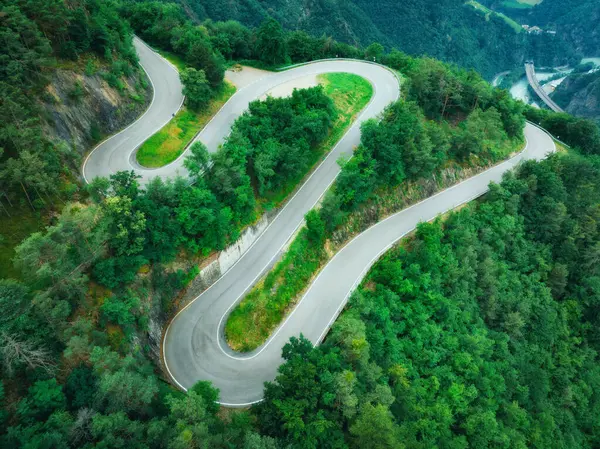 Yazın dağ kıvrımlı yolu ve yeşil ormanın havadan görünüşü. Dolomitler, İtalya. Dağ geçidindeki virajlı yol manzarası, baharda ağaçlar. Ormandan geçen yol. Karamsar, yol manzaralı