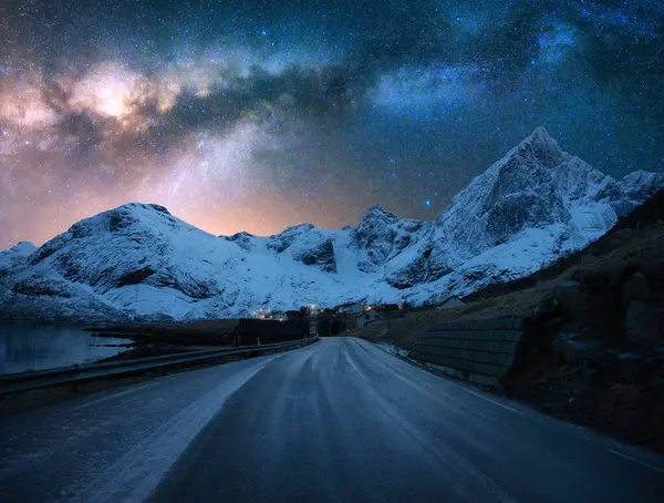 Yol üzerinde parlayan Samanyolu, kışın Lofoten, Norveç 'te yıldızlı gecede karlı dağlar. Parlak yıldızlı gökyüzü ve karlı kayaların üzerindeki Samanyolu. Kutup renklerinde bir manzara. Kış Harikalar Diyarı. Boşluk