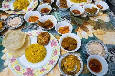 Tabaklar renkli Bengali mutfağıyla dolup taşıyor, Luchi, Pulao ve bir dizi lezzetli yemek, canlı bir aşçılık deneyimi yaratıyor.