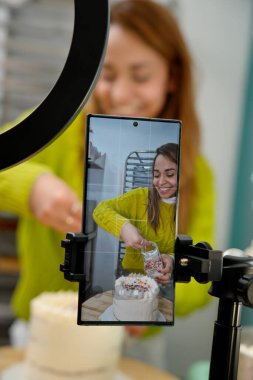 İspanyol kadın pastayı hazırlarken cep telefonuyla kendini filme çekiyor.