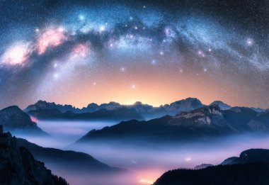 Samanyolu geceleri alçak bulutlarda dağların üzerinde kemer gibidir. Alp Dağı Vadisi 'nin sisli manzarası. Samanyolu ile yıldızlı gökyüzü. Aydınlanma. Hava görüntüsü. Passo Giau, Dolomitler, İtalya. Boşluk. Üst görünüm