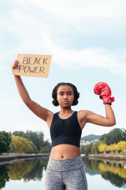 Boks eldivenli genç Afrikalı Amerikalı sporcu göl kenarındaki antrenmandan sonra üzerinde Siyah Güç yazıları olan bir pankart gösteriyor.