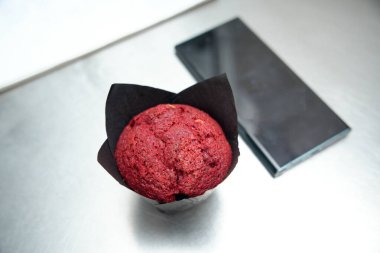 Çelik masadaki cep telefonunun yanında kırmızı kadife kek.