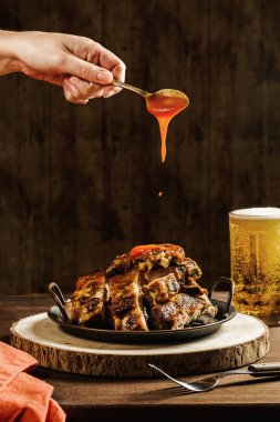 Tanınmayan bir aşçı kafeteryada servis edilen barbekü pirzolalarına ketçap döküyor.