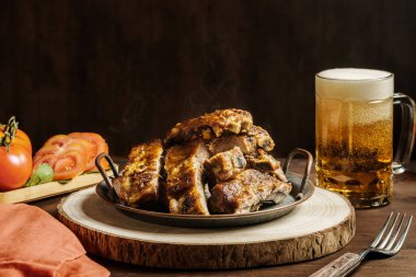 Tahtaya konmuş nefis domuz kaburgaları, sebzeler ve bir bardak taze bira.