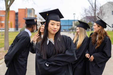 Akademik önlüklerini ve şapkalarını takmış gururlu mezunlar mezuniyet gününde akademik başarılarını kutluyorlar.