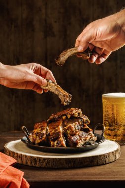 Lezzetli ızgara domuz pirzolası yiyen ve kafede yemek yiyen insanların elleri.