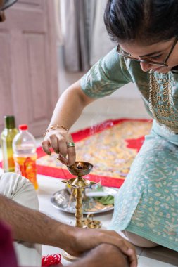 Geleneksel bir dini tören sırasında tütsü çubuklarıyla bir diya yakan Hintli kadın.