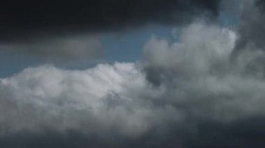 Karanlık, uğursuz fırtına bulutlarının hızlı oluşumunu ve hareketini gösteren bir zaman kayması videosu çalkantılı bir gökyüzünde toplanıyor, gerçek zamanlı değişen hava modellerini gösteriyor..