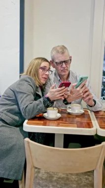 Entellektüel engelli iki yetişkin bir kafede yan yana oturup, akıllı telefonlarına bakıyorlar. Dijital eklenti ve karşılıklı destek gösteriyorlar..