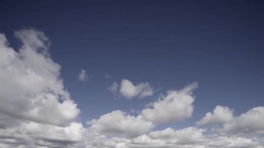 Derin mavi gökyüzünde canlı beyaz bulutların hızlı hareketini gösteren ve doğal güzelliği ve hareket halindeki atmosferik dinamikleri gösteren bir zaman dilimi videosu..