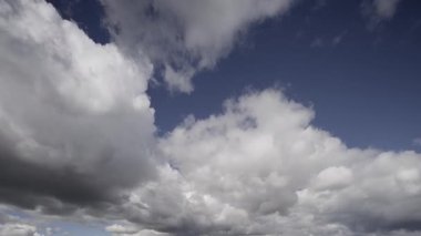 Bu zaman ayarlı video bulutların dramatik ve hızlı bir şekilde mavi gökyüzünün arkaplanına doğru hareket ettiğini gösteriyor, büyüleyici bir ekranda havanın doğal dinamiklerini gösteriyor..
