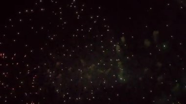 Canlı bir havai fişek, parıldayan yıldızların ortasındaki altın ve turuncu renklerle gece gökyüzünü aydınlatıyor..