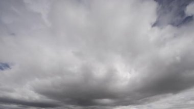 Çarpıcı bir zaman dilimi videosu beyaz kümülüs bulutlarının canlı mavi gökyüzünde hızlı hareketlerini ve dönüşümlerini yakalıyor, doğal dinamikleri ve hava durumlarını gösteriyor..