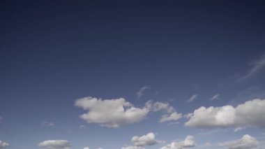 Zaman çizelgesi, beyaz kabarık bulutların hareketli hareketlerini yakalar açık mavi gökyüzünde sürüklenerek, doğanın dinamik ama dinamik güzelliğini gösterir..