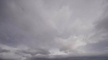 Karanlık fırtına bulutlarının dinamik hareketlerini yakalayan, gri bulutlu bir gökyüzünde biriken, potansiyel bir fırtınanın gerçek zamanlı oluşumunu resmeden bir zaman videosu..