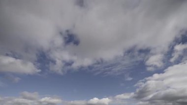 Fırtınalı bulutların dinamik hareketlerini gösteren zaman dilimi videosu açık mavi bir gökyüzünün arkaplanına doğru yuvarlanıyor, gerçek zamanlı hava değişimlerini gösteriyor..
