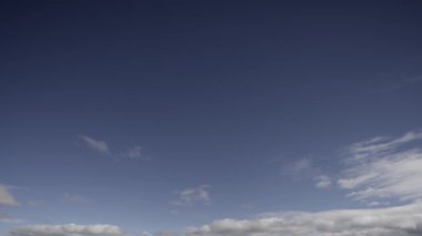 Zaman çizelgesi görüntüleri, çeşitli bulutların dinamik hareketlerini yakalıyor açık mavi bir gökyüzünde sürükleniyor, zamanın huzurlu geçişini ve atmosferik güzelliğini gösteriyor..