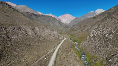 Andes 'in geniş dağ manzaralarını görüntüleyen hava aracı görüntüleri. Video geniş, engebeli arazi ve akarsu arasında dar bir patikayı vurguluyor.