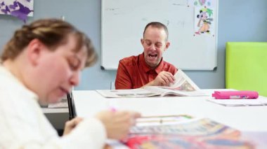 Zihinsel engelli insanlar bir gündüz merkezinde yaratıcı ve eğitici faaliyetlerde bulunurlar. Sanat ve okuma oturumlarına katılırlar, öğrenme ve sosyal etkileşimi teşvik ederler..