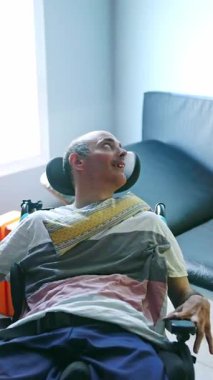 Fiziksel ve zihinsel engelli bir adam, terapi rutininin bir parçası olarak, dinlenme odasında, dinlenme odasında rahat bir şekilde gülümseyerek ve huzurlu bir andan zevk alır.