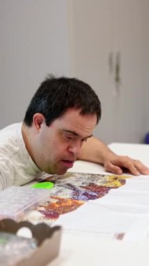 Zihinsel engelli yetişkin bir adam, bir gün merkezinde renkli bir elmas resmi tamamlamaya odaklanır. Terapi sanatı ile odak, sabır ve yaratıcılığı teşvik eder..