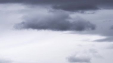 Bu zaman ayarlı video, gökyüzünde hızla ilerleyen ve dramatik ve sürekli değişen bir hava sahnesi sunan koyu ve kabarık beyaz bulutların dinamik hareketini yakalar..