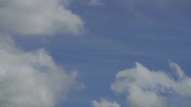 Beyaz ve gri bulutların parlak mavi gökyüzünde hızlı ve dramatik bir şekilde hareket edişini gösteren ve doğal olayları gerçek zamanlı olarak gösteren bir zaman kaydıdır..