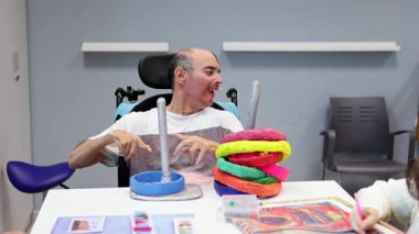 Bu video, zihinsel engelliler için bir gündüz merkezindeki etkinlikleri gösteriyor, destekleyici bir ortamda yaratıcılık, bakım ve sosyal bağlantıyı vurguluyor.