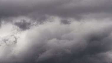 Gökyüzünde yoğun, karanlık fırtına bulutlarının dramatik ve hızlı bir şekilde toplandığını gösteren bir zaman kaydıyla yaklaşan fırtınayı gösteriyor..