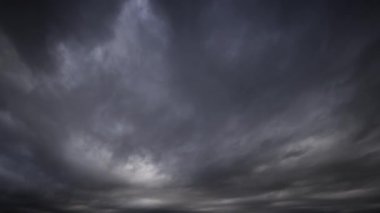 Gökyüzünde yoğun, karanlık fırtına bulutlarının dramatik ve hızlı bir şekilde toplandığını gösteren bir zaman kaydıyla yaklaşan fırtınayı gösteriyor..