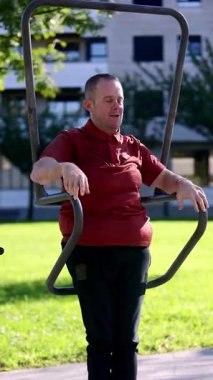 Bir adam, dinlenme ve terapi için zihinsel engelli kişilere sunulan etkinlikleri ve desteği vurgulayarak, bir gündüz merkezindeki açık hava egzersiz ekipmanlarıyla neşe içinde meşgul olur..