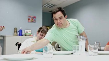 Zihinsel engelli yetişkinlerden oluşan bir grup günlük yaşam becerilerine sahiptir. Bağımsızlık, işbirliği ve sorumluluğu desteklemek için bir günlük merkezde masayı bir araya getirirler.