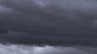 Kasvetli bir gökyüzünde toplanan karanlık ve yoğun fırtına bulutlarının hareketli havanın dinamik doğasını gösteren dramatik zaman dilimi videoları gösteriyor..