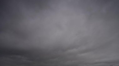 Gökyüzünde yoğun, karanlık fırtına bulutlarının dramatik ve hızlı bir şekilde toplandığını gösteren bir zaman kaydıyla yaklaşan fırtınayı gösteriyor..