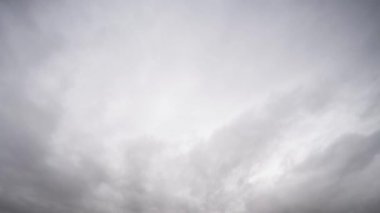 Yoğun, kabarık bulutların dinamik hareketlerini yakalayan ve yumuşak gri bir gökyüzünde sürüklenen video gerçek zamanlı doğal bir görüntü sunuyor..