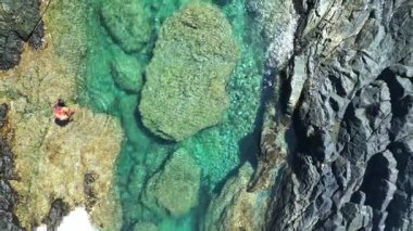 Tanımlanamayan bir kadın, Fuerteventura, Kanarya Adaları 'ndaki Aguas Verdes' in doğal yeşil havuzlarında yüzüyor. Gerçek zamanlı bir insansız hava aracı tarafından havada yakalandı.
