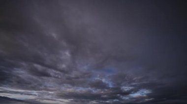 Karanlık, fırtınalı bir gökyüzünde bulutların hızlı hareketini ve dönüşümünü gösteren, ışıktan yoğunluğa değişimleri gösteren dramatik bir zaman dilimi videosu..