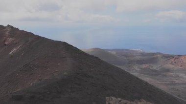 İspanya, La Palma 'nın dramatik volkanik arazisi engebeli tepeleri geniş bir okyanus zeminiyle ve bulutlu gökyüzüyle sergiliyor, doğal güzelliği ve sakin izolasyonu yakalıyor..