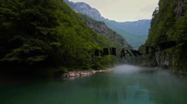 Karadağ 'ın yemyeşil dağları ve sakin nehrinin büyüleyici hava manzarası. Sis yavaşça yükselir, sakin, resimsel bir manzara yaratır. Doğa meraklıları için mükemmel..