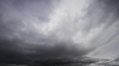 Ağır, fırtınalı bulutların dinamik hareketlerini gösteren bir zaman kaydıyla karanlık bir gökyüzü boyunca ilerlerken hava koşullarındaki hızlı değişimleri gösteriyor..