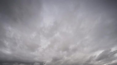 Ağır, fırtınalı bulutların dinamik hareketlerini gösteren bir zaman kaydıyla karanlık bir gökyüzü boyunca ilerlerken hava koşullarındaki hızlı değişimleri gösteriyor..