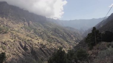 La Palma 'nın engebeli dağlarının görkemli manzarası ve bulutlu gökyüzünün altındaki yemyeşil vadiler adanın el değmemiş doğal güzelliğini ve dramatik arazisini gözler önüne seriyor..