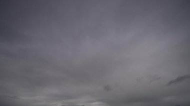 Ağır, fırtınalı bulutların dinamik hareketlerini gösteren bir zaman kaydıyla karanlık bir gökyüzü boyunca ilerlerken hava koşullarındaki hızlı değişimleri gösteriyor..