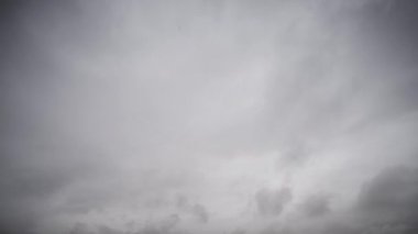 Ağır, fırtınalı bulutların dinamik hareketlerini gösteren bir zaman kaydıyla karanlık bir gökyüzü boyunca ilerlerken hava koşullarındaki hızlı değişimleri gösteriyor..