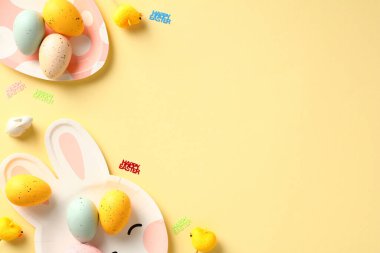 Mutlu Paskalya kompozisyonu. Düz Paskalya yumurtaları ve masa örtüsü sarı arka planda servis edilir..
