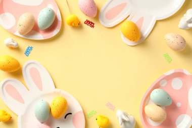 Mutlu Paskalya kartı şablonları. Sarı arka planda renkli Paskalya yumurtaları ve sofra takımı servis ediliyor.