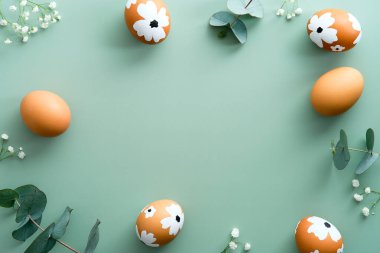 Mutlu Paskalya kartı tasarımları. Paskalya yumurtaları, okaliptüs yaprakları ve pastel yeşil arka planda çiçeklerden yapılmış çerçeve..